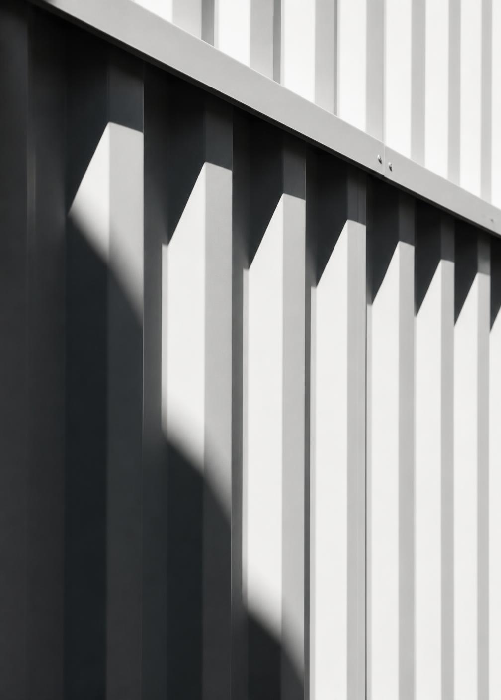 Raking light across profiled metal cladding on a completed facade